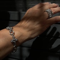 a woman's hand holding a silver bracelet and ring